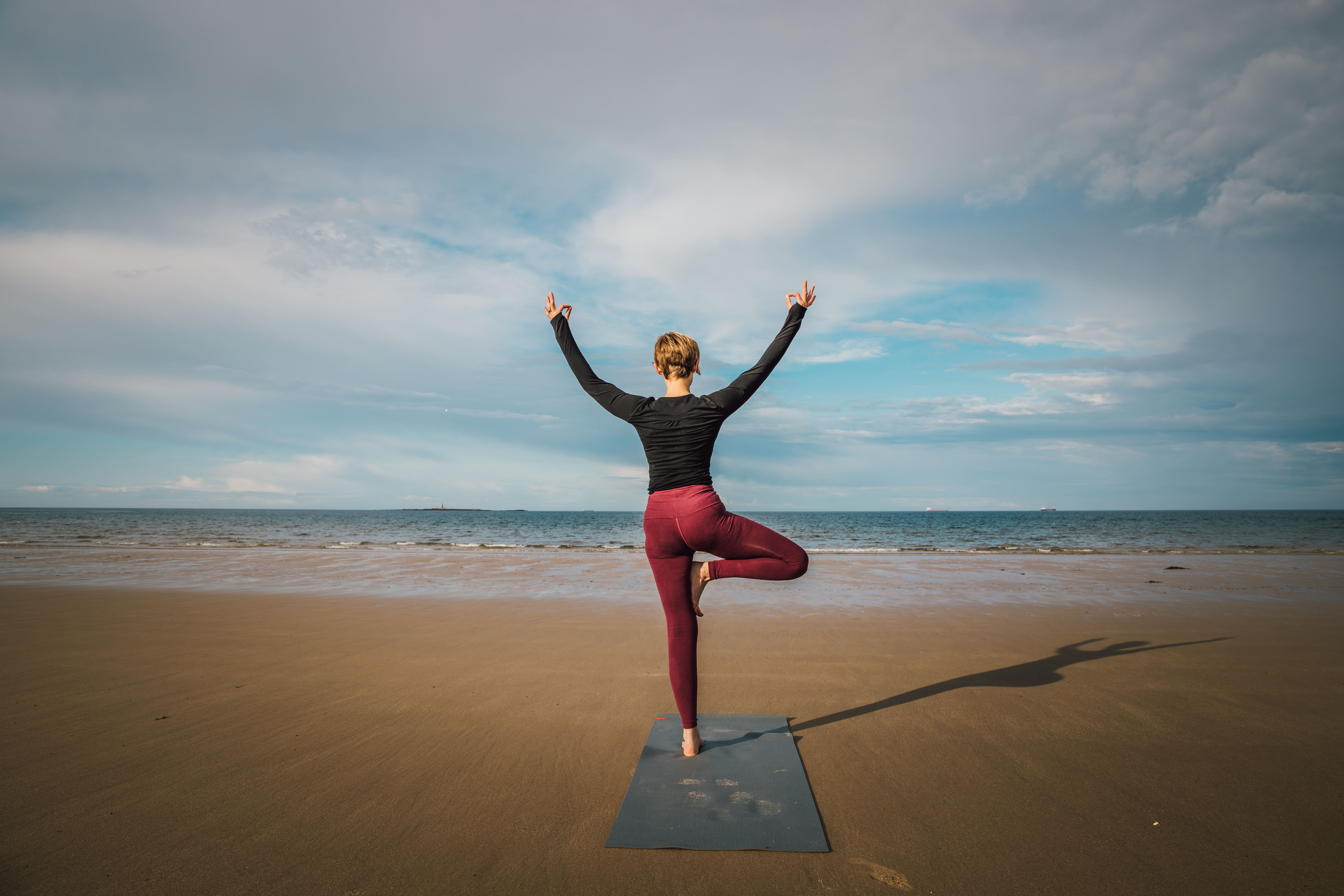 Woman practising yoga on the beach