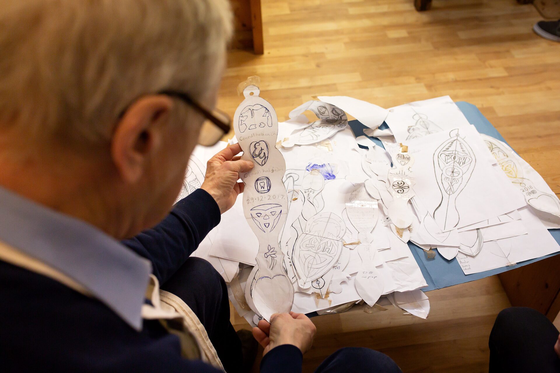 Person yn cymryd rhan mewn gweithgaredd celf ar bwrdd.