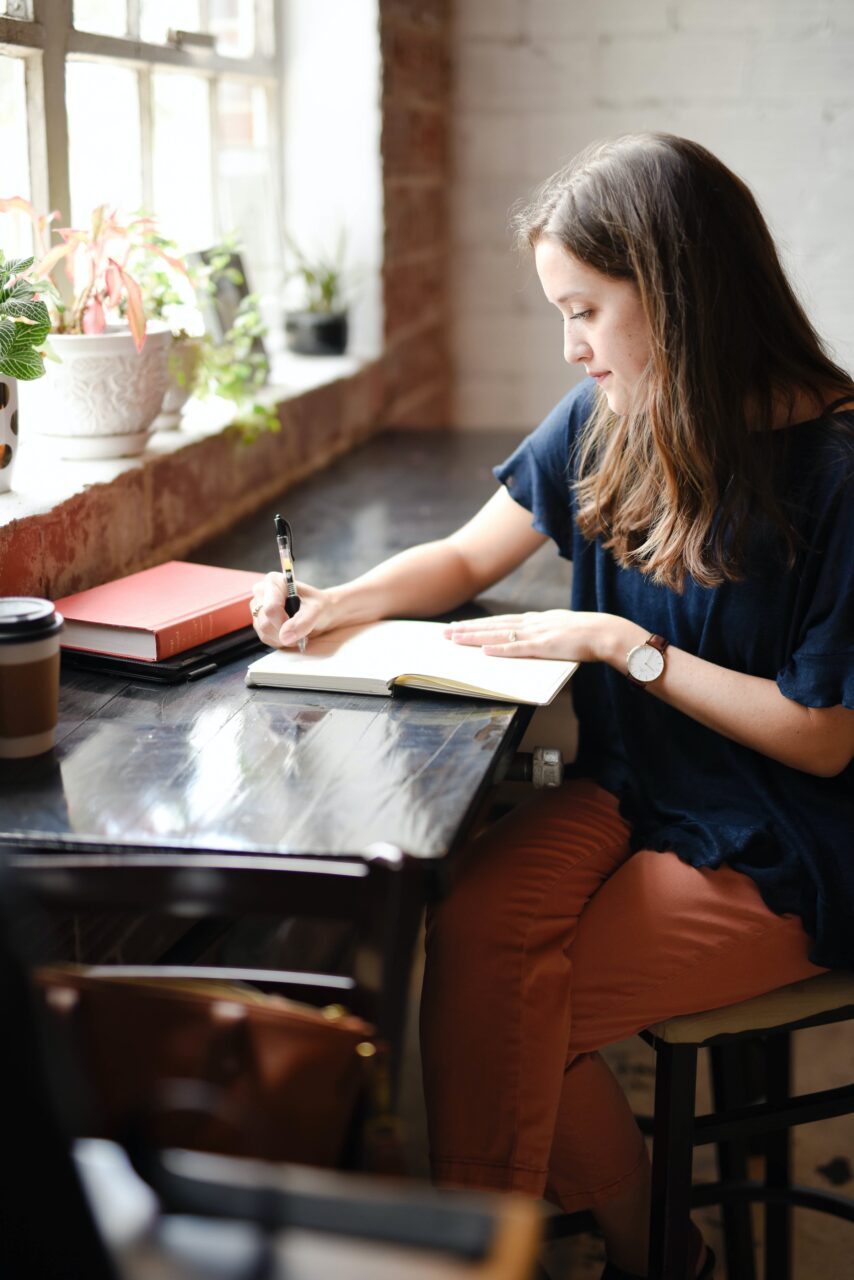 A person sitting in a cafe and writing in a book