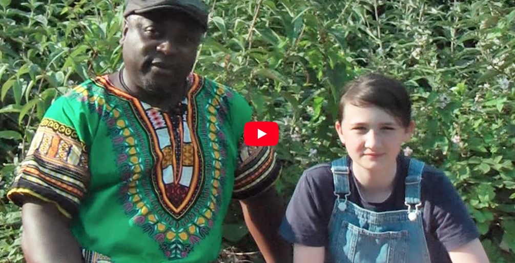 Llun llonydd wedi’I gymryd o’ fideo ‘Visceral Storytelling – Poetry, Songs and Storytelling’ sy’n dangos dyn yn eistedd nesaf I berson ifanc.