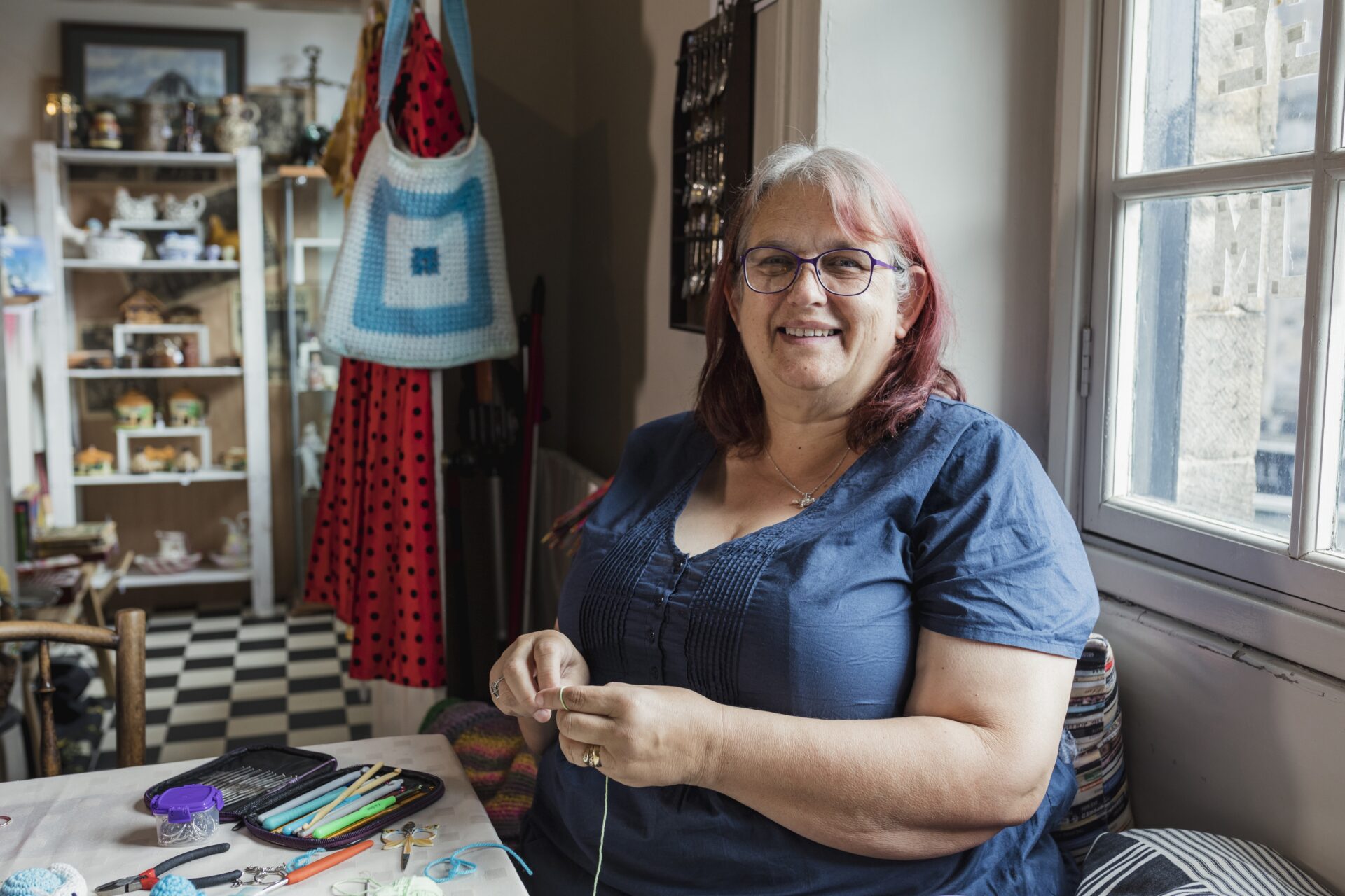 A person sat at a table with crochet equipment
