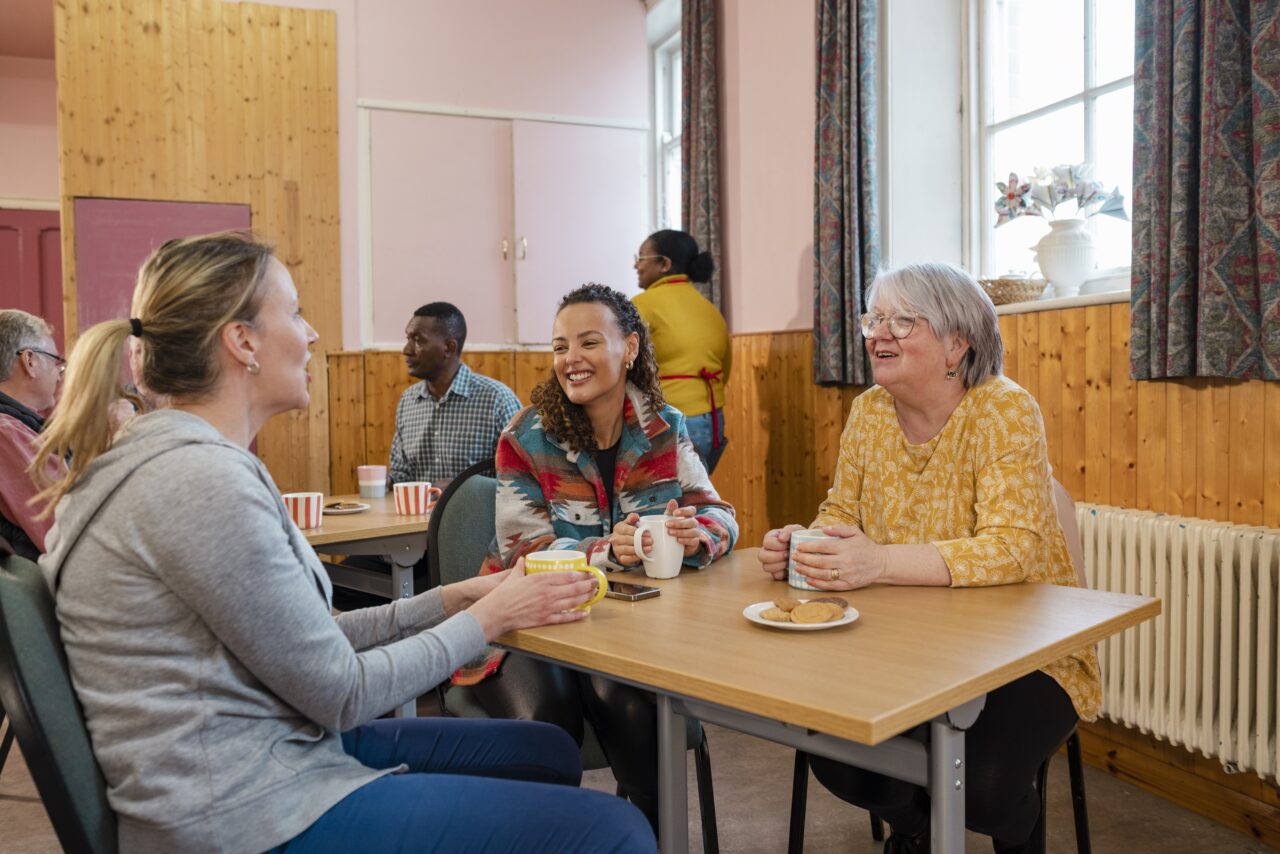 A group of people talking to each other in a community centre.