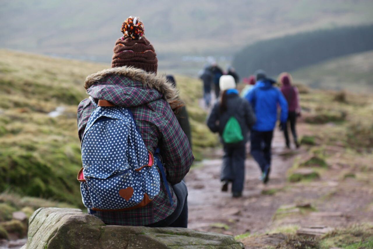 A person sitting on a rock to rest while hiking with a group of people.