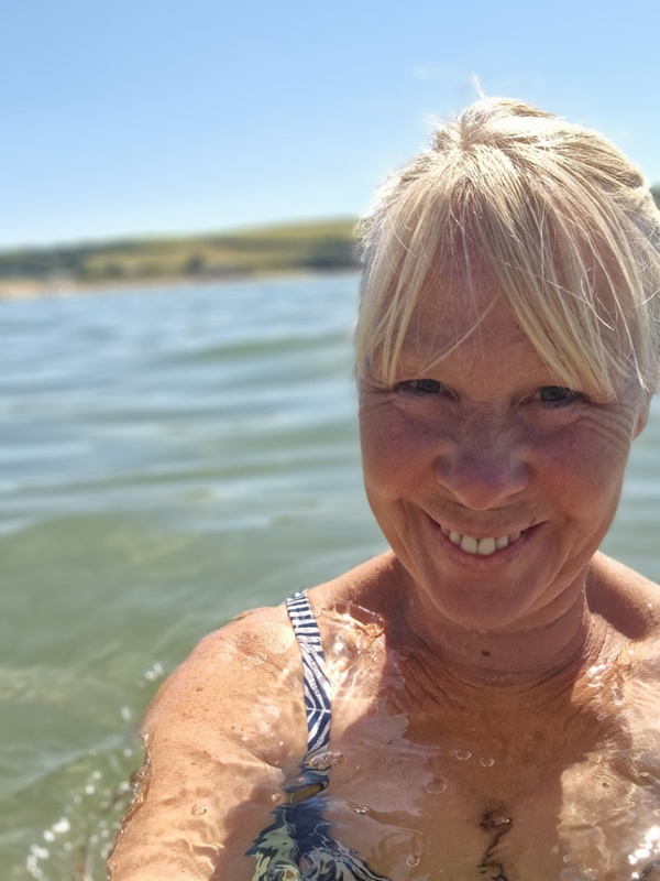 Menyw yn cymryd llun o'i hun yn y mor.