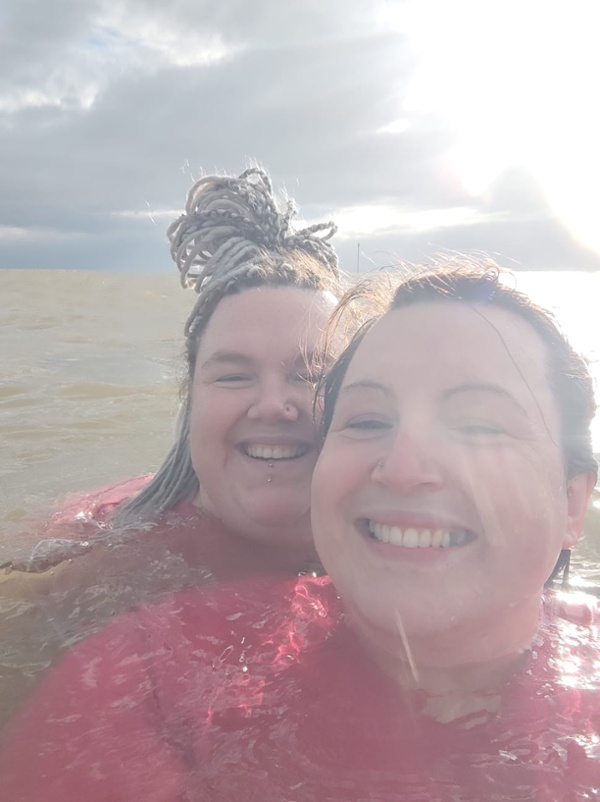 Dau menyw yn cymryd llun o'u hun yn y mor.