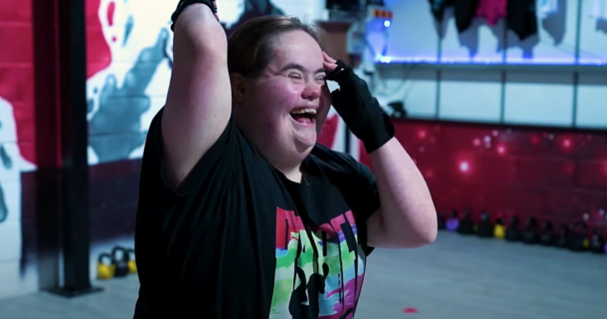 Actor Hijinx, Bethany Freeman, yn sefyll gyda'i breichiau lan, wrth i hi chwerthin gan sefyll mewn stiwdio dawns.